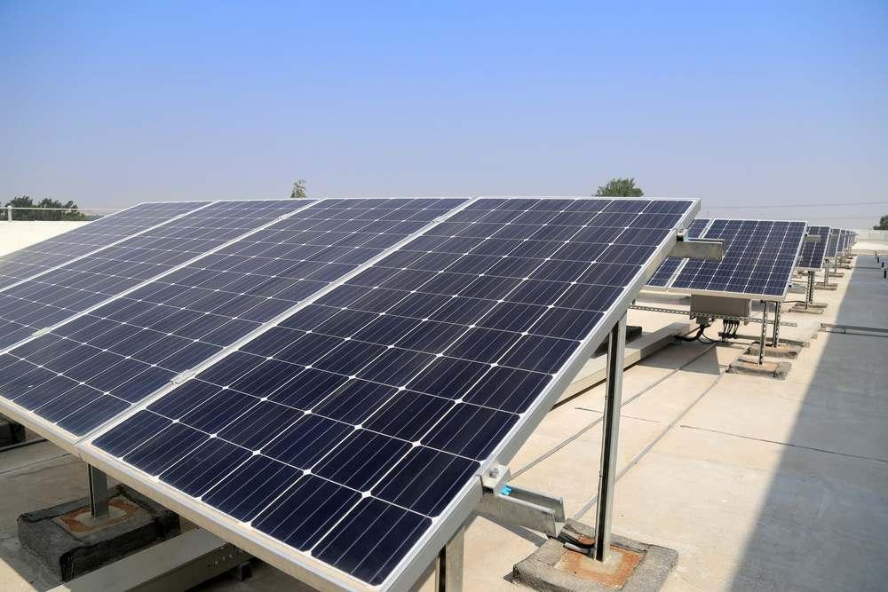 Vista completa de una instalación fotovoltaica terminada sobre el tejado de una vivienda unifamiliar, mostrando los paneles, el inversor en la pared y el cableado