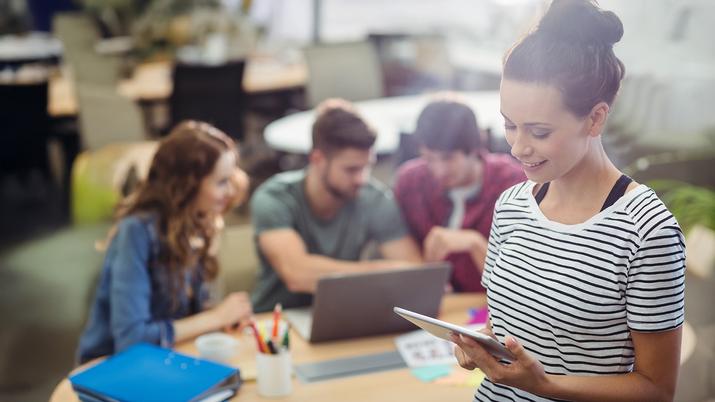 Estudiante utilizando una tablet con lápiz digital para realizar una tarea escolar en un aula luminos