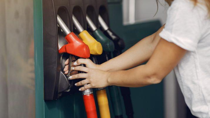 Mujer repostando gasolina sin plomo 95 en un surtidor de una estación de servicio moderna