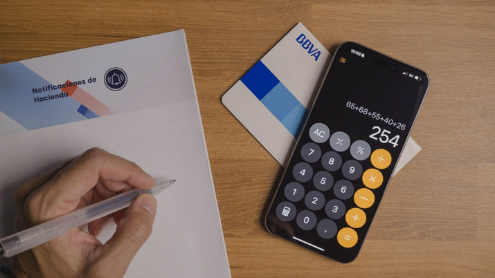 Persona utilizando una calculadora y un bolígrafo sobre documentos de una hipoteca para analizar los tipos de interés fijo