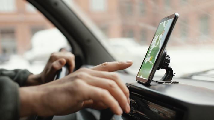 Conductor cometiendo una infracción al mirar y manipular un smartphone con GPS mientras conduce por una autopista