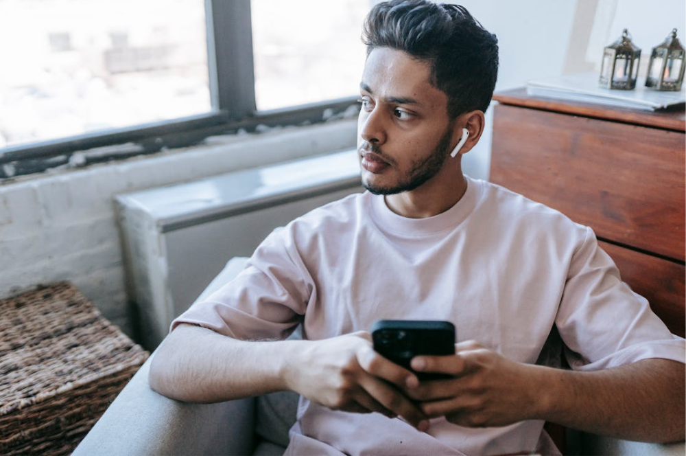 hombre usando auriculares inalámbricos con móvil en la mano