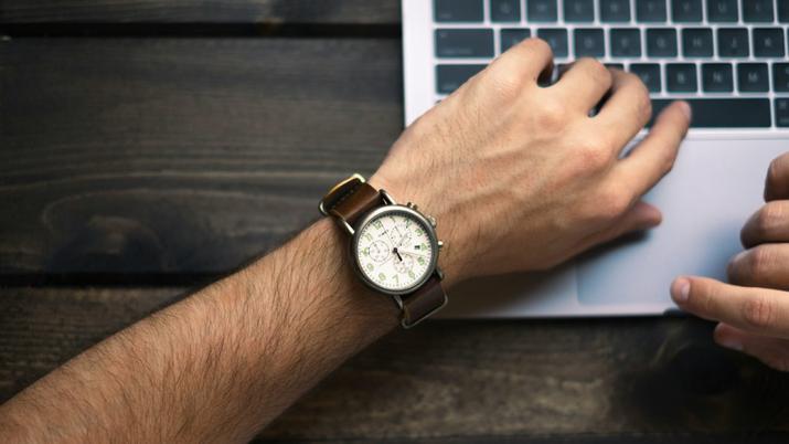 Una persona usa un ordenador con un reloj en la muñeca.