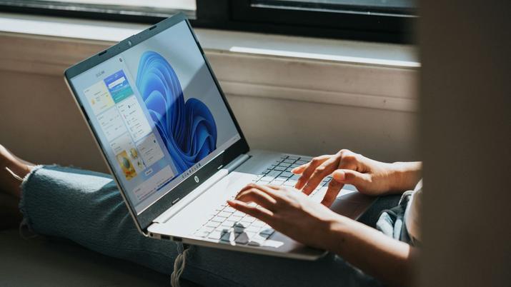 Una chica tumbada tecleando en su portátil con Windows