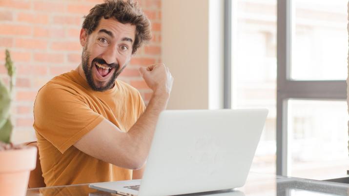 hombre feliz con portátil en su casa